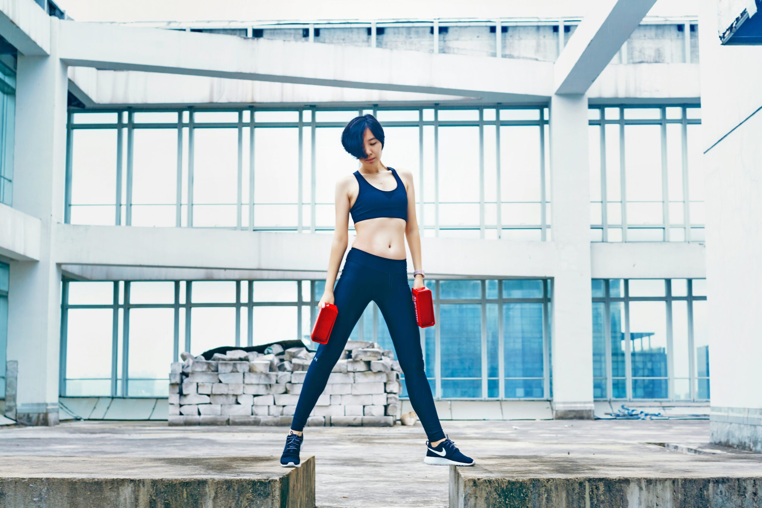 A model wearing sleek black activewear from Bloomingdale's striking a pose against a minimalist backdrop.
