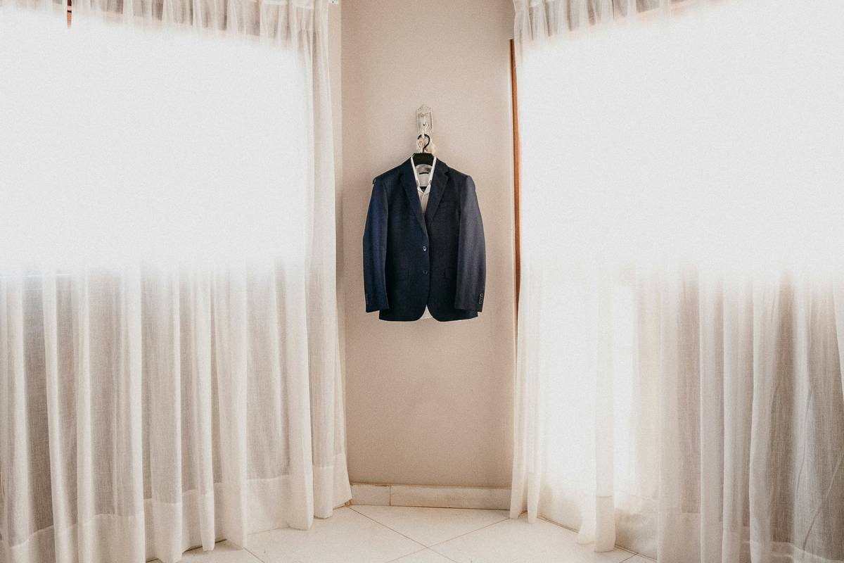Infographic showing correct vs incorrect suit jacket storage methods with hanger types, humidity levels, and fabric stress points