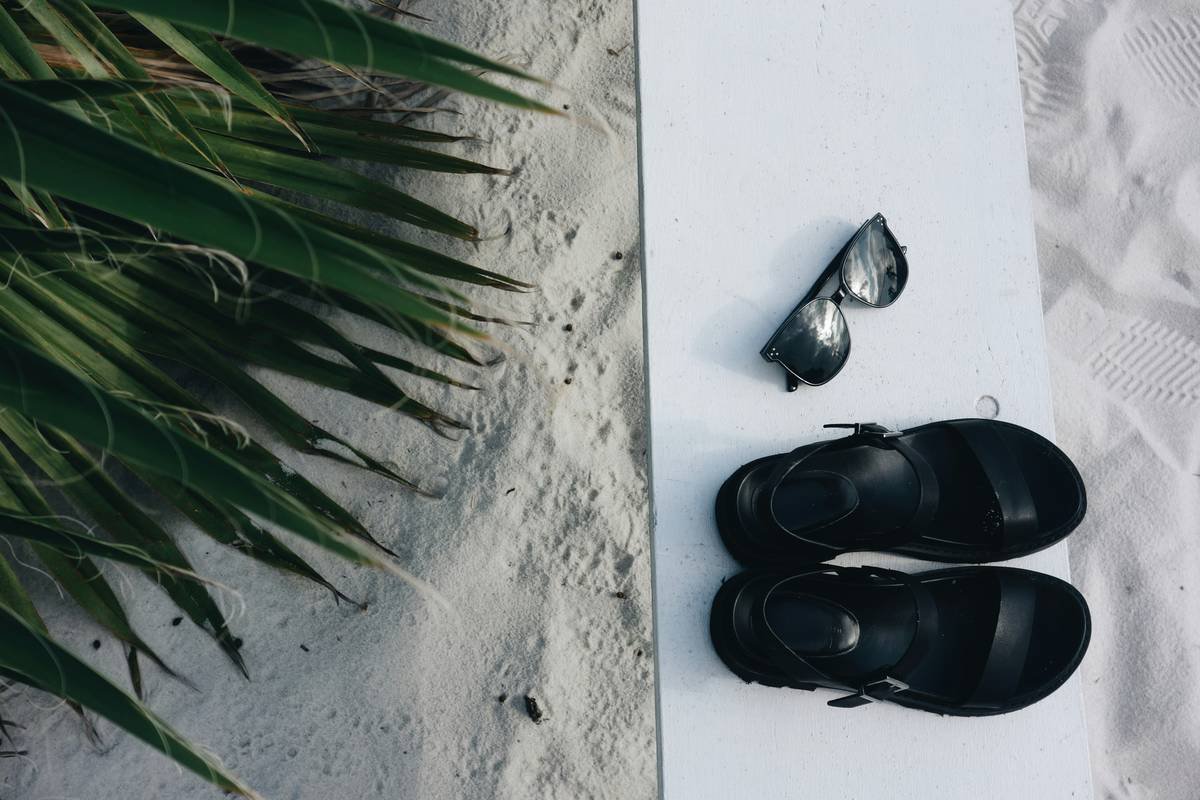 Infographic showing ideal capsule shoe collection: 5-7 pairs including walking sneakers, ankle boots, loafers, sandals, and one statement pair—all in neutral tones with wellness features labeled